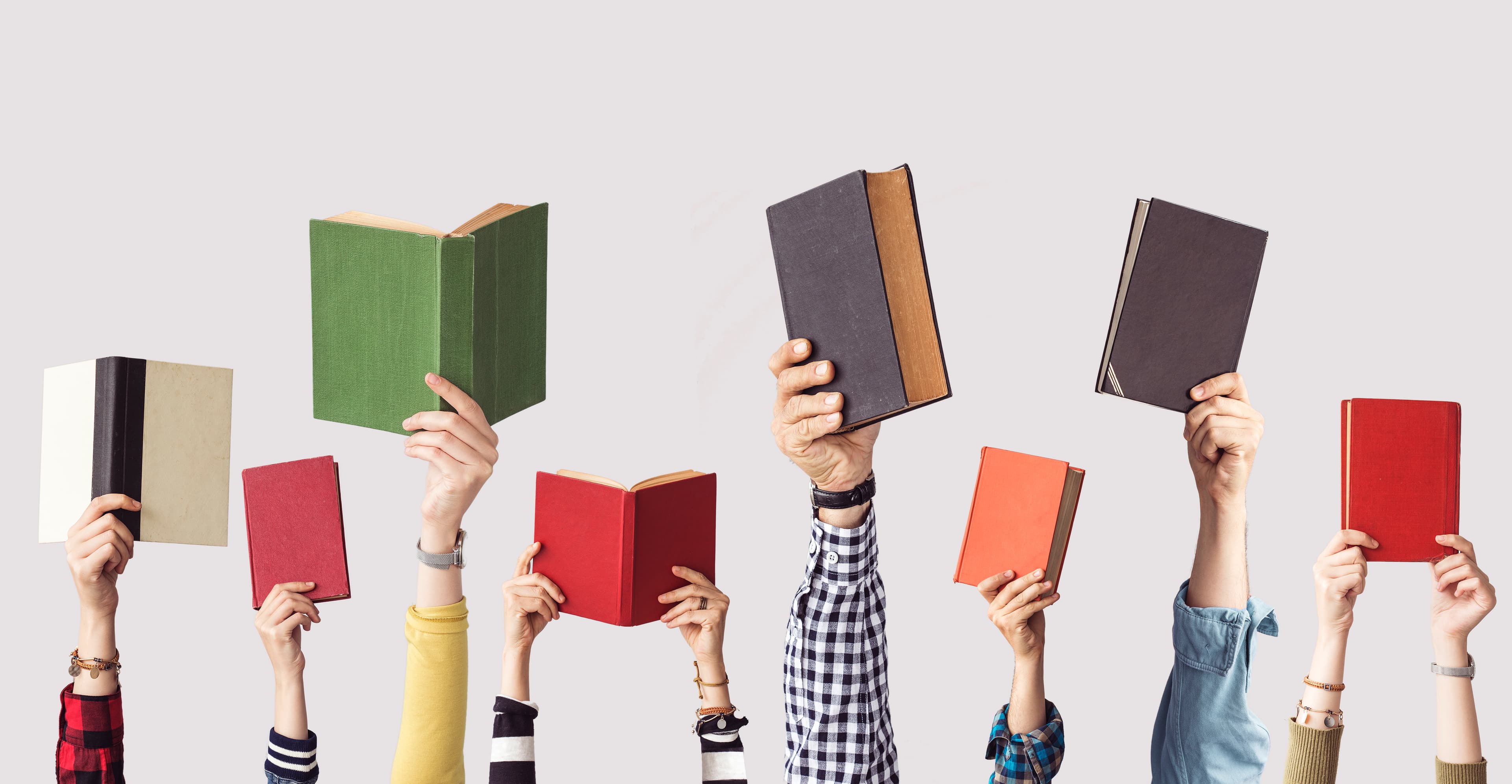 Hands holding books up to the sky.