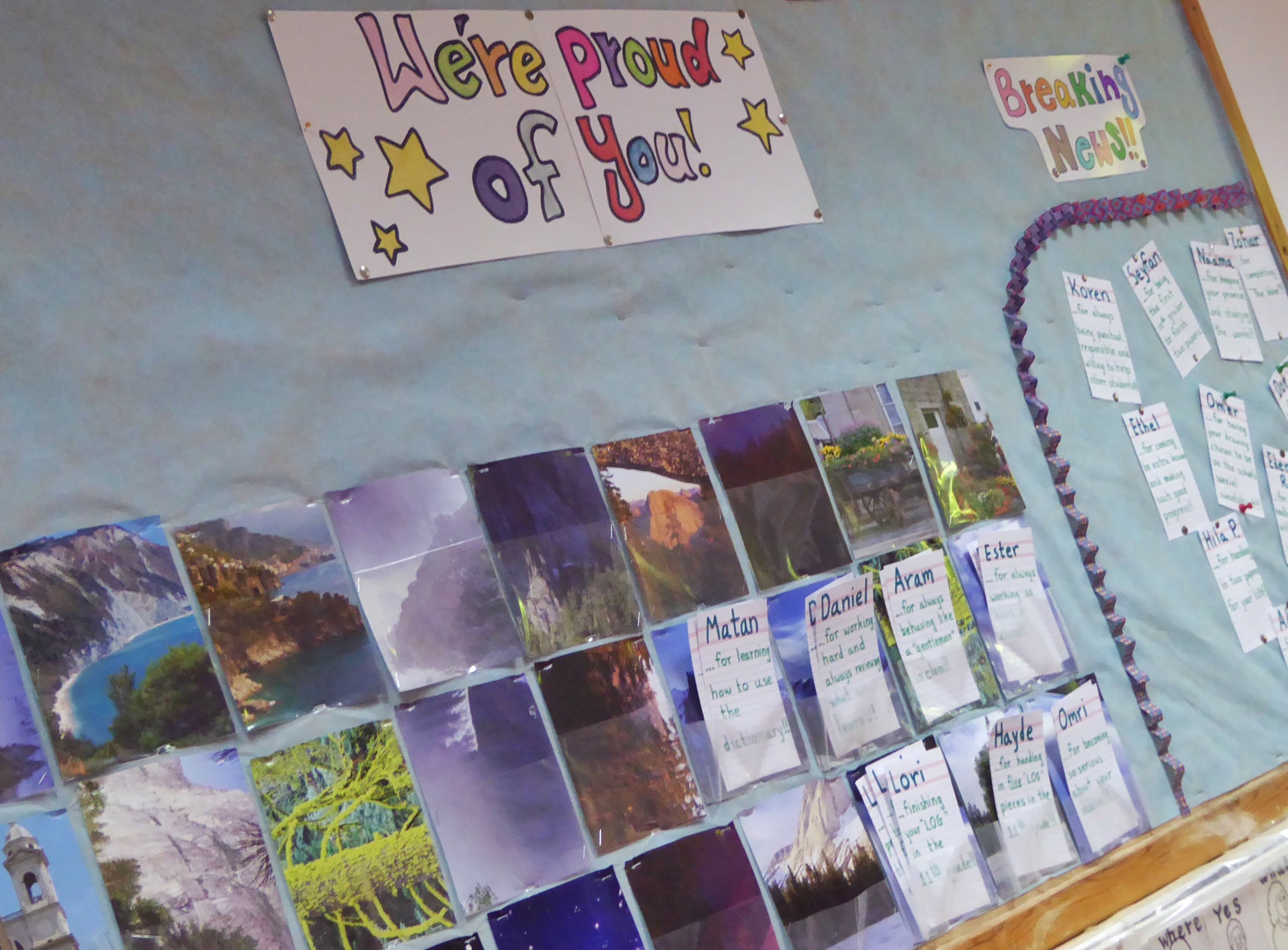 A classroom board with 'a sign reading 'we're proud of you' in colourful letters in the middle.