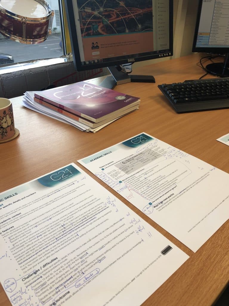 Two sheets of paper with C21 Academic Skills markup on. A stack of C21 books are in the background, too.