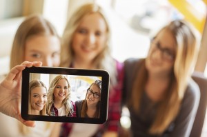 Three cheerful friends taking photos of themselves on digital tablet