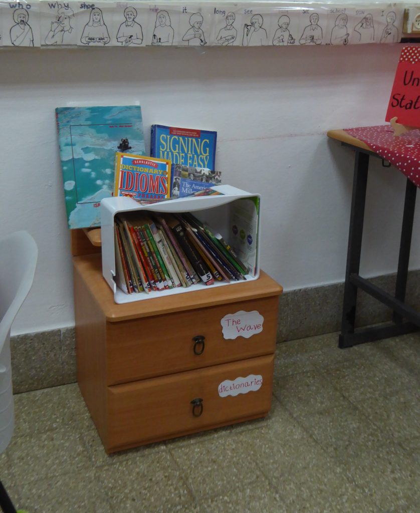 A corner of the classroom, with sign language translation cards, and a stack of books about sign language, idioms, and other classroom resources.