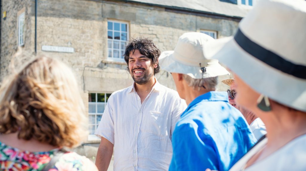 A male tour guide smiling and talking to people.