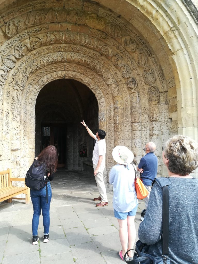 A tour guide showing some people a large, grand stone door of a building.