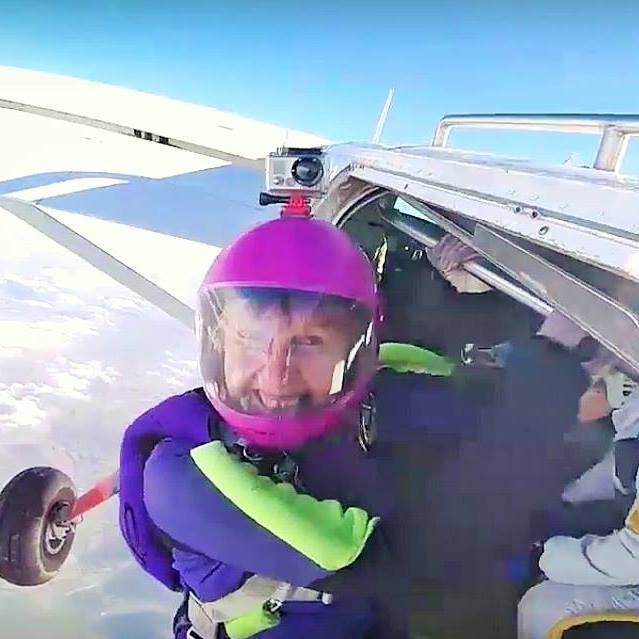 A woman jumping out of a plane to go skydiving.