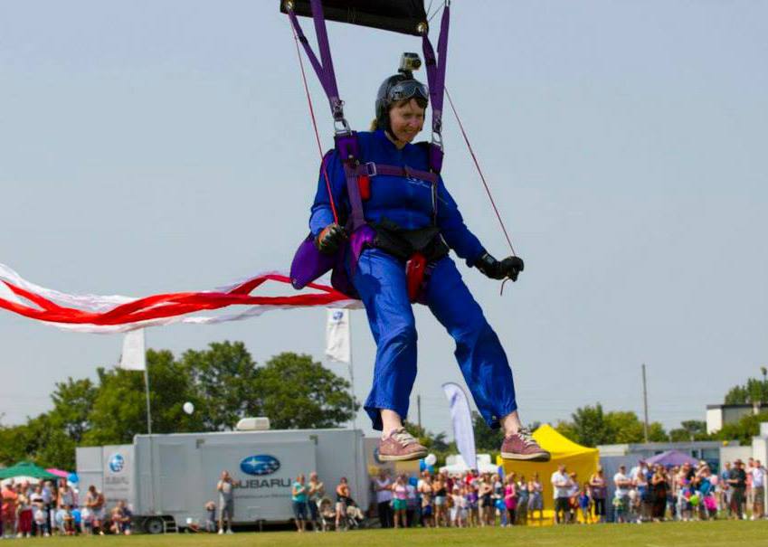 A woman coming into land a skydive at a show with spectators in the background.