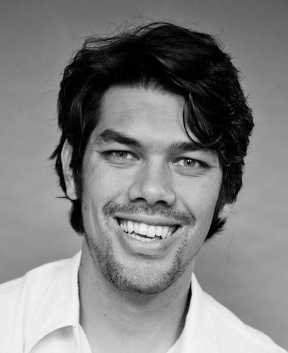 A black and white photo of Jules, a dark-haired man smiling.