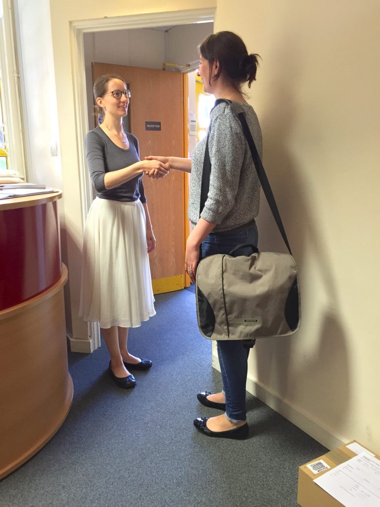 Two women shaking hands, posing for a picture.