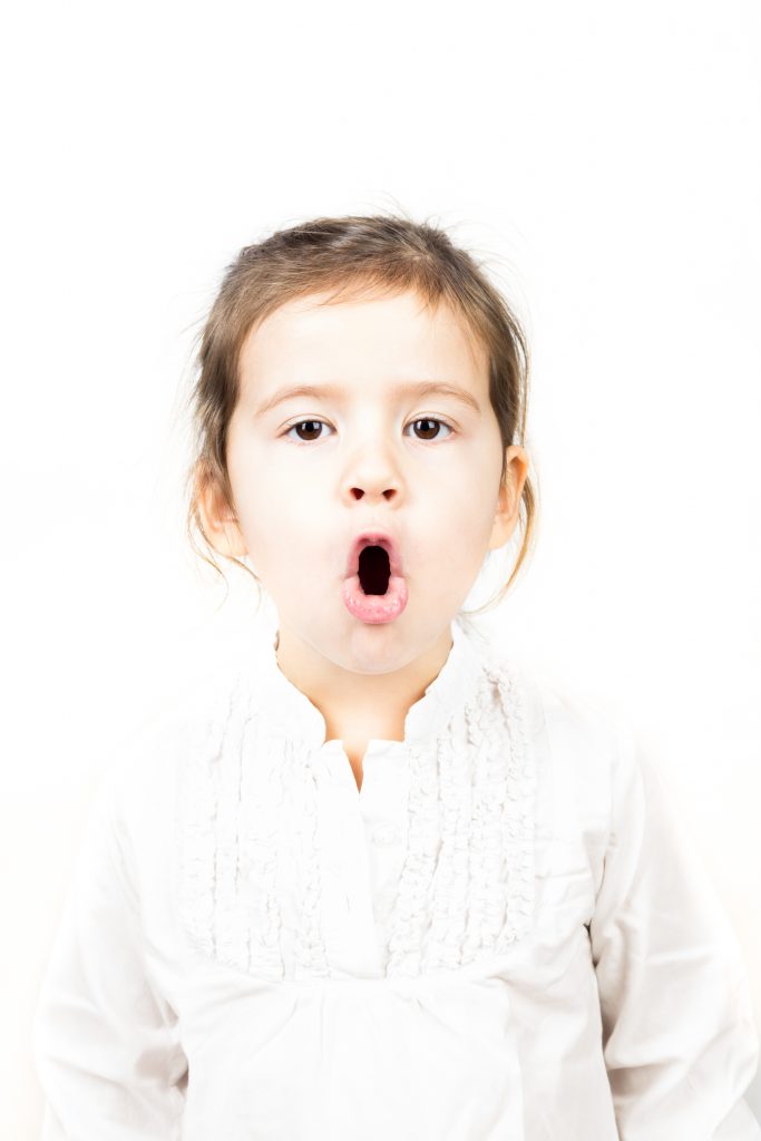 A small girl making an 'o' shape with her mouth.