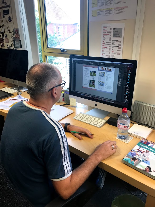 A middle aged man making changes to Coursebook using InDesign